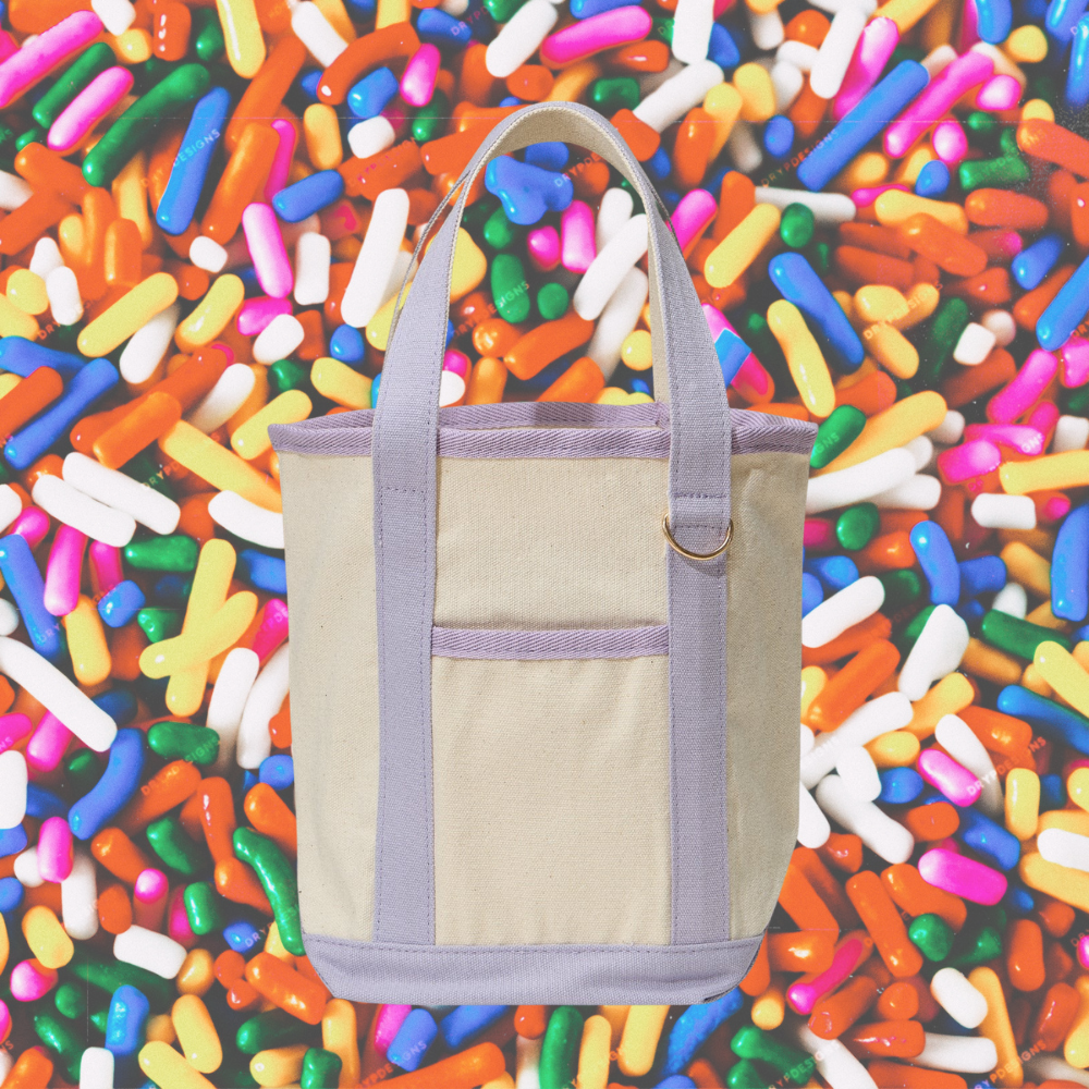 Beige tote bag with purple accents on a colorful sprinkles background
