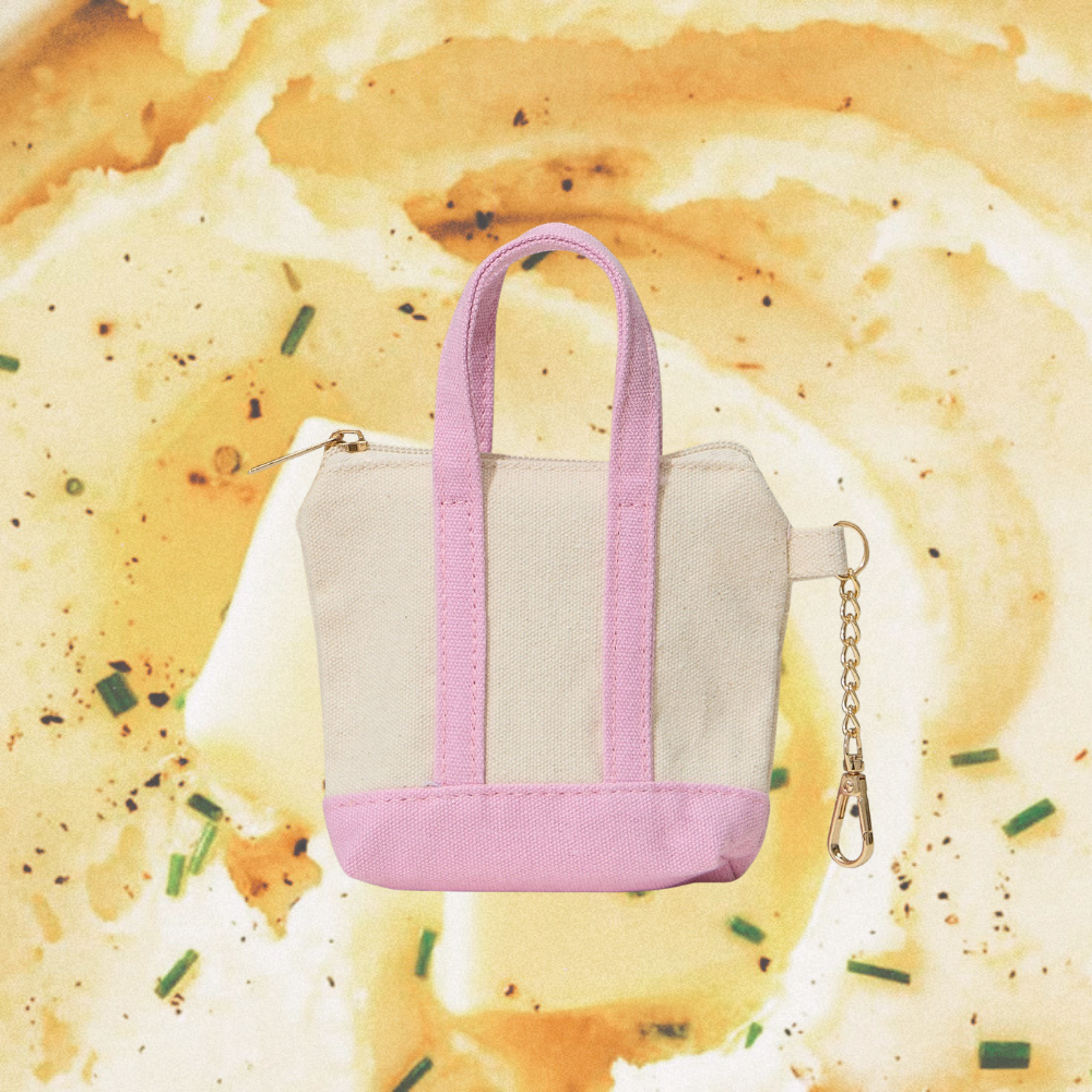 Small bag keychain with pink straps and beige base on a mashed potato background